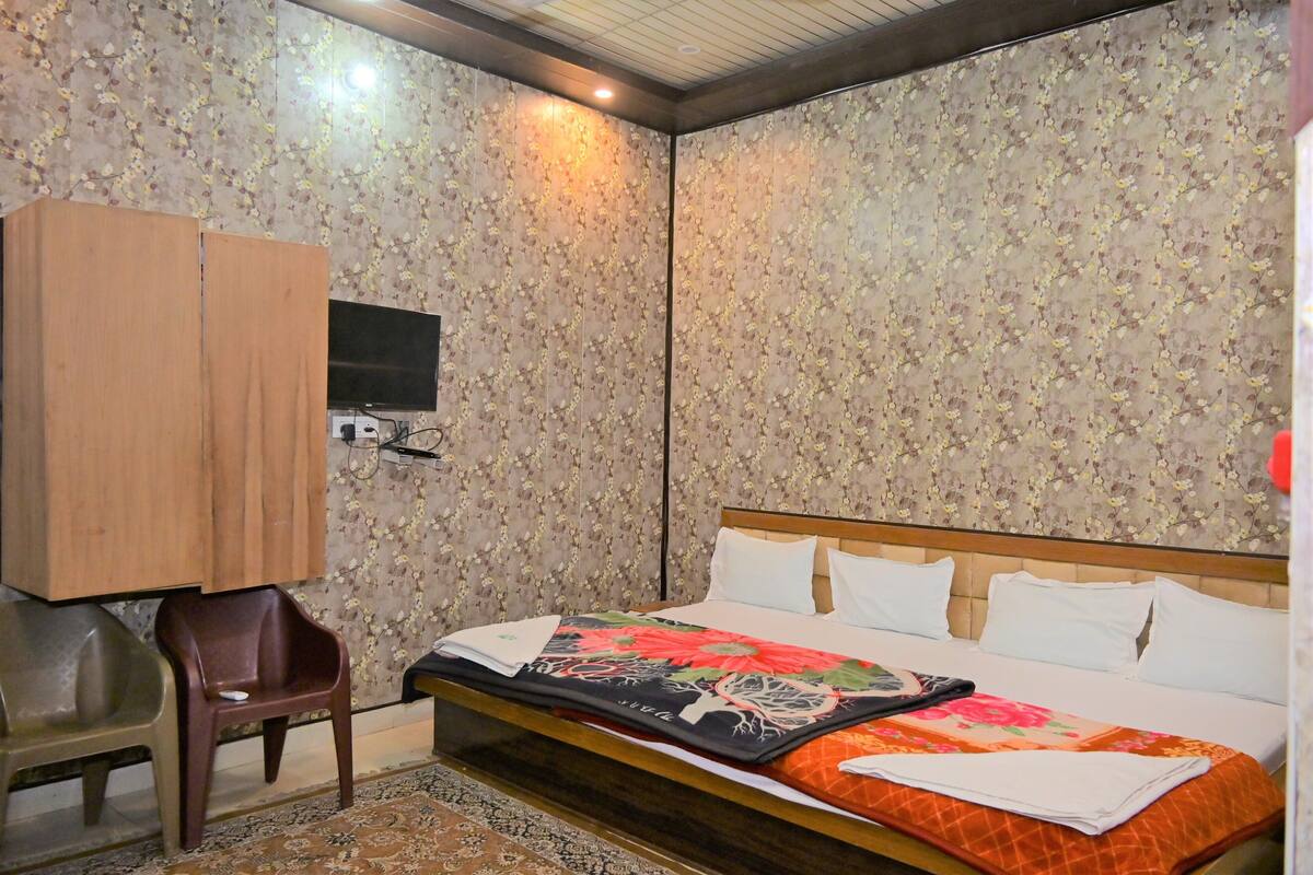 Un dormitorio con una cama, televisor, armario y una silla.