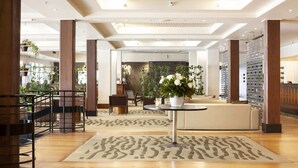 A spacious lobby with a central seating area, wooden pillars, and a patterned rug. - Stylish Studio with Full Kitchen on Hobson Street (Auckland Central)