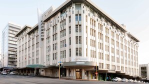 A large, multi-story hotel with a prominent entrance and a sign reading 'Heritage.' - Stylish Studio with Full Kitchen on Hobson Street (Auckland Central)