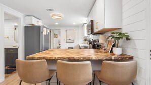 Une cuisine moderne dotée d’un grand îlot central, de tabourets de bar et d’une plante en pot.