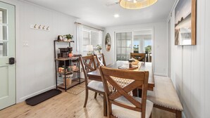 Un espace repas comprenant une table en bois, des chaises et un luminaire suspendu.
