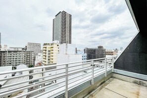 A high-rise building with a balcony overlooking a cityscape. - F-studio VERONICA (Osaka)
