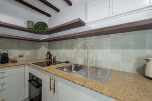 A kitchen with granite countertops, stainless steel sink, white cabinets, and a built-in oven. - Lakes Edge Retreat (Yungaburra)