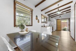 A modern kitchen with wooden beams, a glass dining table, and a view of the outdoors.