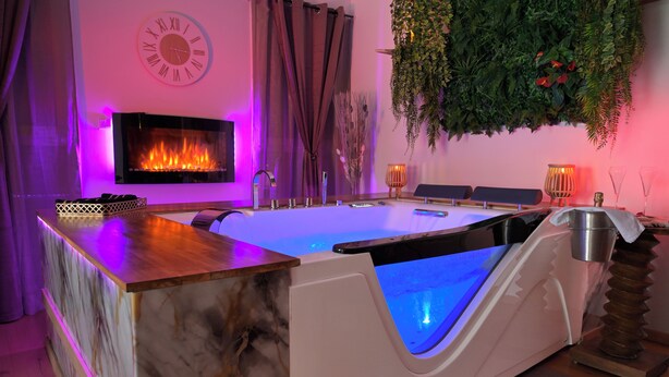 A spa area with a heated pool, a clock, and a plant wall. - Luxury loveroom with private Jacuzzi, sauna, cinema corner & privacy area (Saint-Privat)