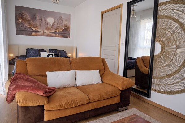 A living room with a sofa, a large mirror, and a painting on the wall.
