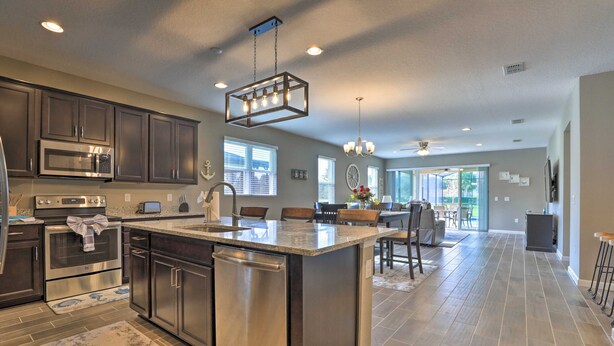 A spacious kitchen with a large island, stainless steel appliances, and a chandelier. - Close to Disney! Home w/ Patio & Community Perks (Davenport)
