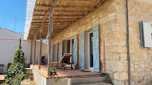 Un bâtiment en pierre doté d’un porche abrité, de poutres en bois et d’une esthétique rustique.