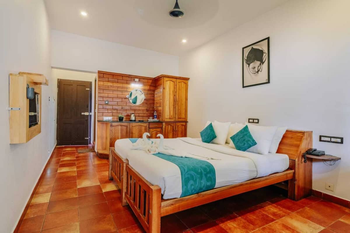 A bedroom with a wooden bed, a small kitchenette, and a bathroom visible through an open door.
