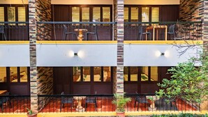A multi-story hotel with balconies, outdoor seating, and a brick facade. - Karar Gardens (Kumily)