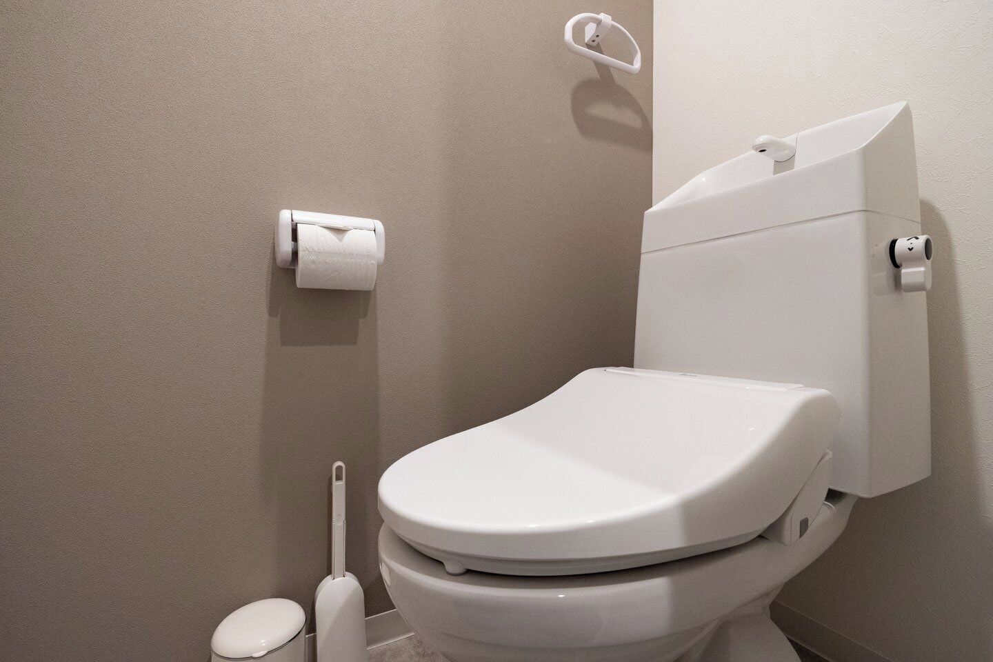 A modern bathroom with a toilet, a toilet paper holder, and a bidet.