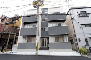 A multi-story residential building with a modern design, featuring balconies, a visible entrance, and a utility pole with various attachments. - Rufura Fukusima (Osaka)