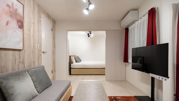 Quarto moderno com sofá, cama, televisão e ar condicionado.