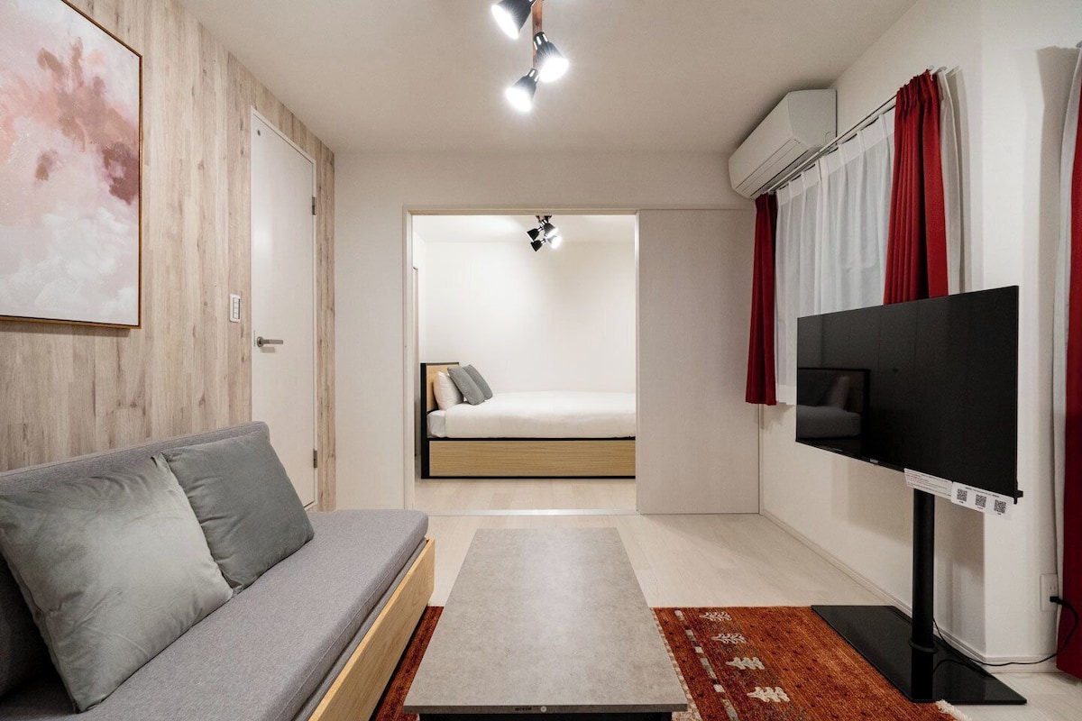 Quarto moderno com sofá, cama, televisão e ar condicionado.