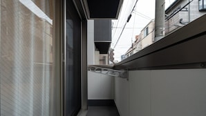 Um corredor estreito com porta deslizante, corrimão de metal e unidade de ventilação.