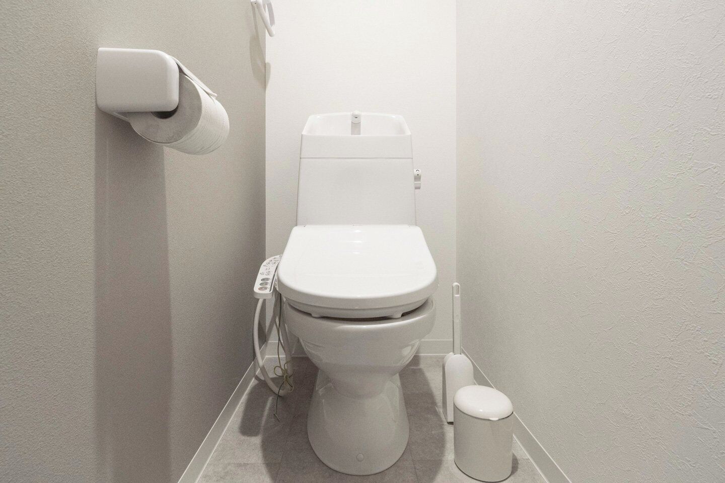 A modern toilet with a flush handle, a toilet paper holder, and a bidet attachment.