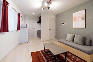 A modern living room with a sofa, a coffee table, and a kitchen in the background. - Rufura Fukusima (Osaka)