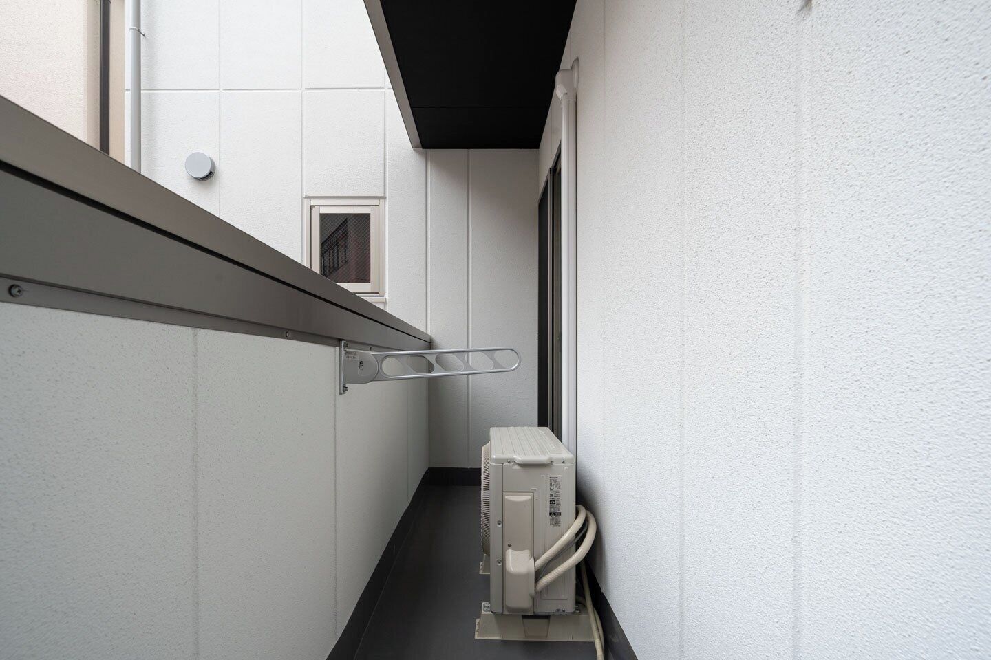 A narrow hallway with a metal handrail, a small window, and a utility box.