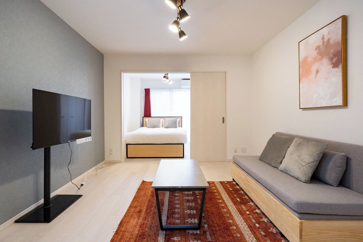 Uma sala de estar moderna com uma TV de tela plana, um sofá, uma mesa de centro e um tapete estampado.