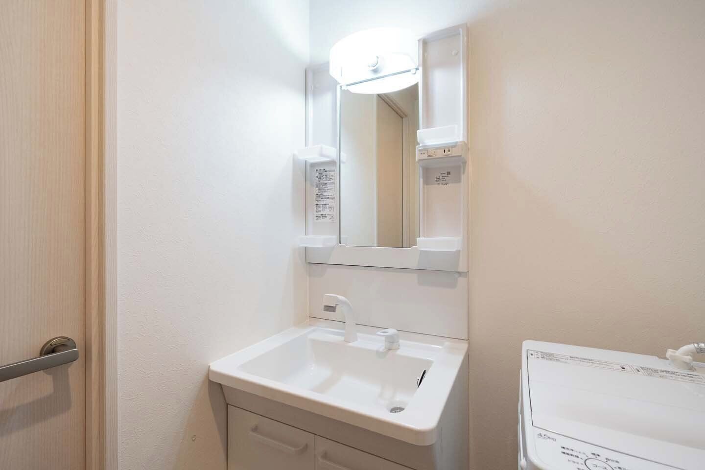 A small bathroom with a white sink, a mirror, and a door.