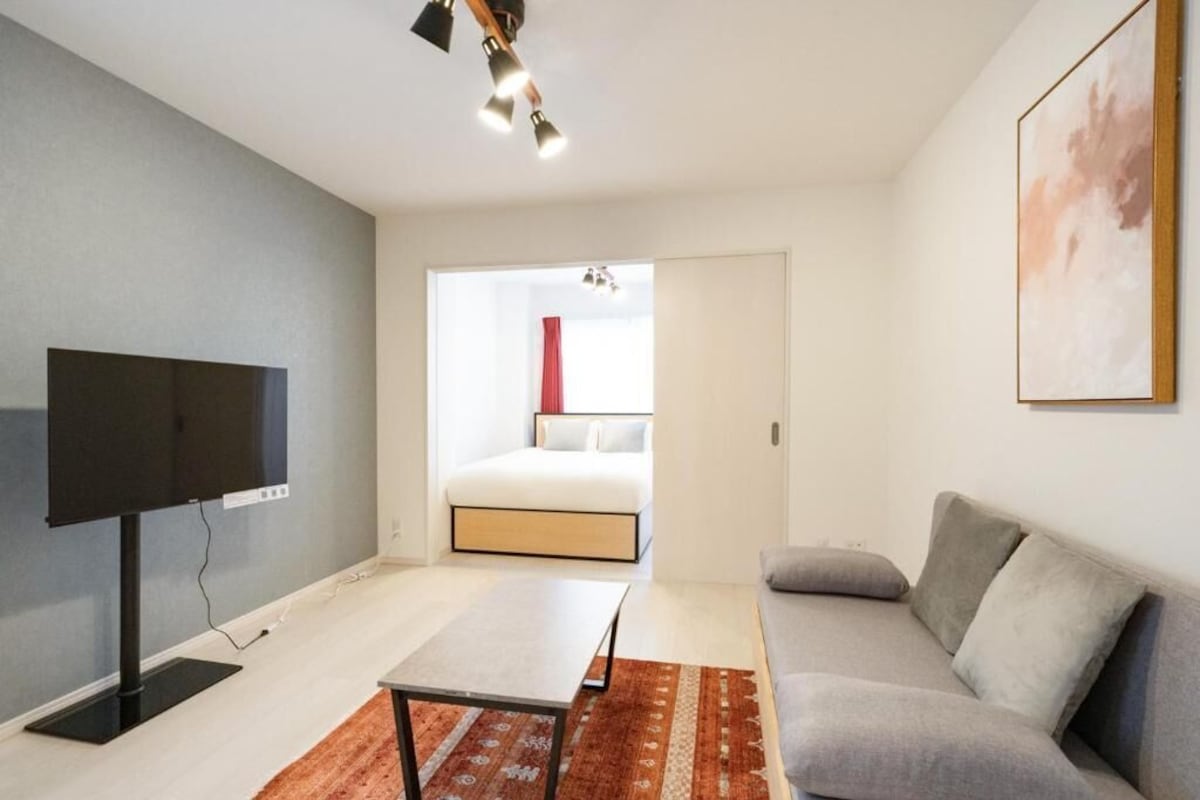 Uma sala de estar moderna com uma TV de tela plana, um sofá, uma mesa de centro e um tapete estampado.
