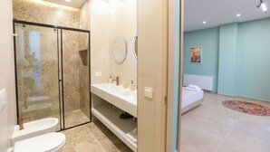 Een moderne badkamer met een douchecabine van glas, een witte wastafel en een ronde spiegel.
