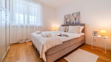 A bedroom with a bed, bedside lamps, a bedside table, and a window with curtains.