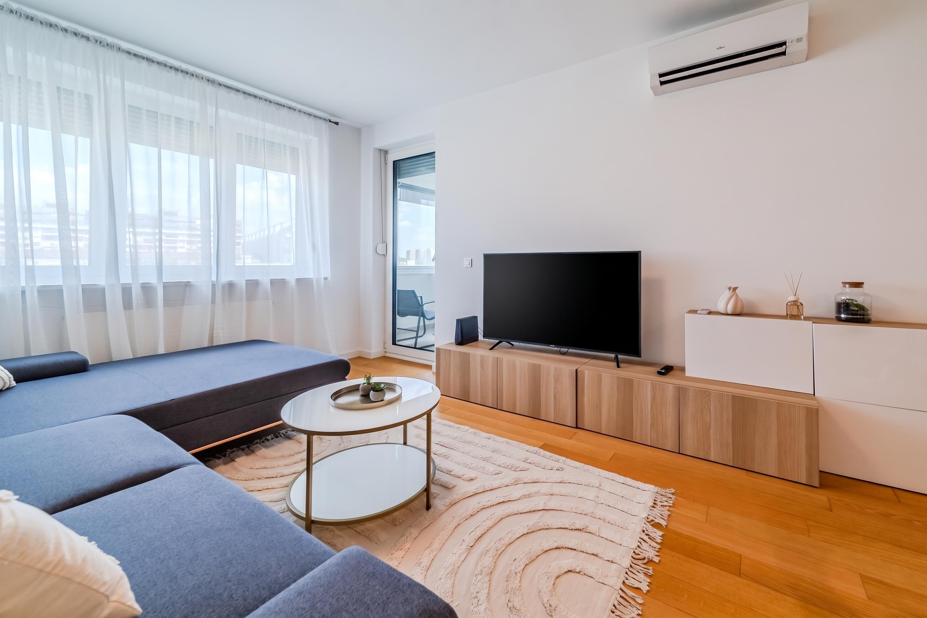 A modern living room with a sofa, a TV, a small table, and a white cabinet.
