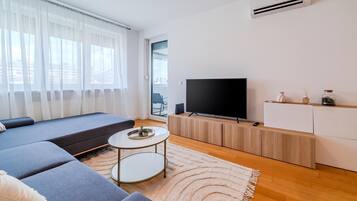 A modern living room with a sofa, a TV, a small table, and a white cabinet.