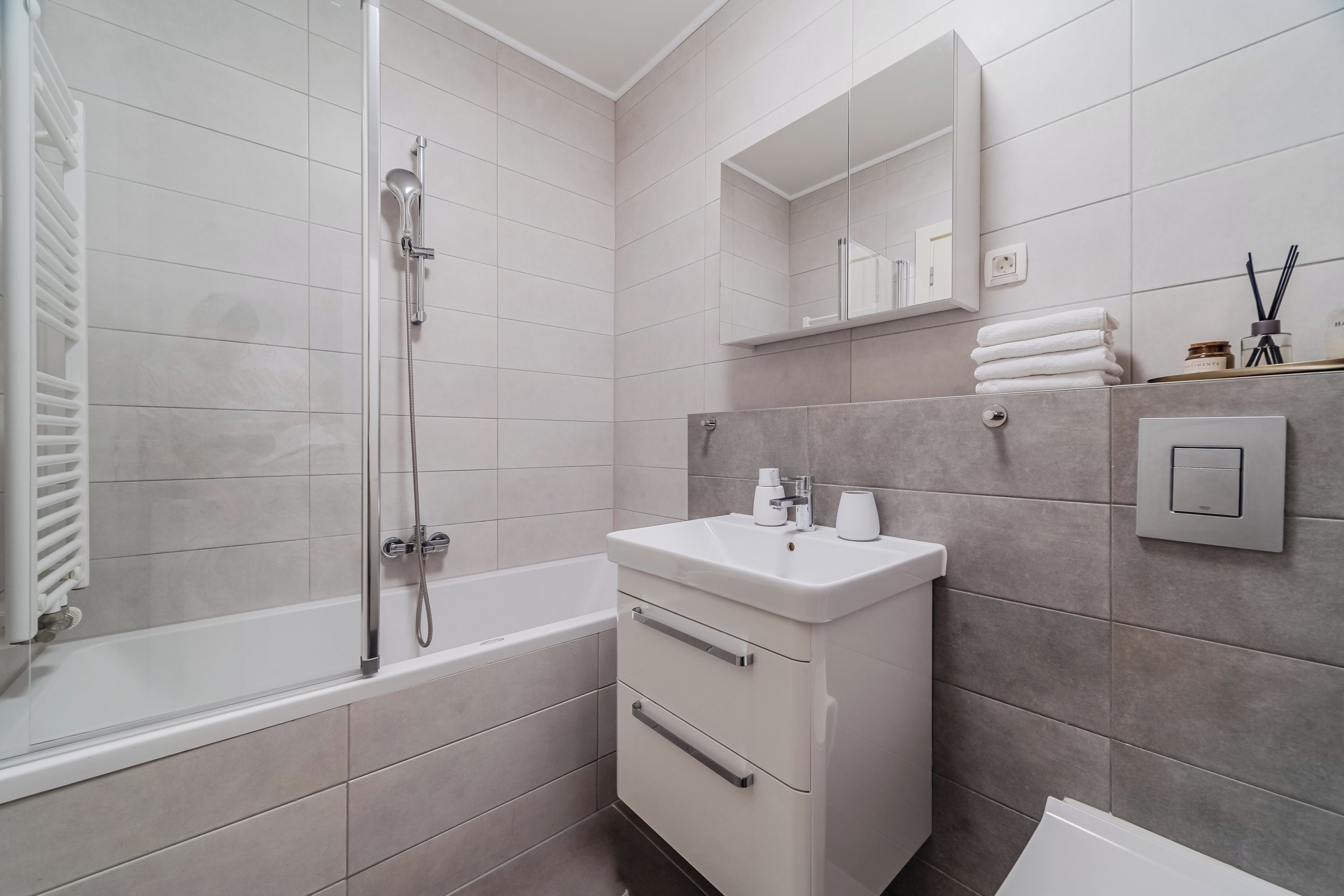 A modern bathroom with a bathtub, a sink, and a mirror.