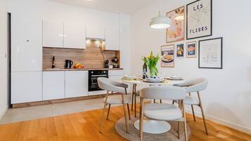 A modern kitchen with white cabinets, a wooden countertop, and a dining area with a round table and chairs.