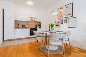 Una cocina moderna con armarios blancos, encimera de madera y un comedor con una mesa redonda y sillas.