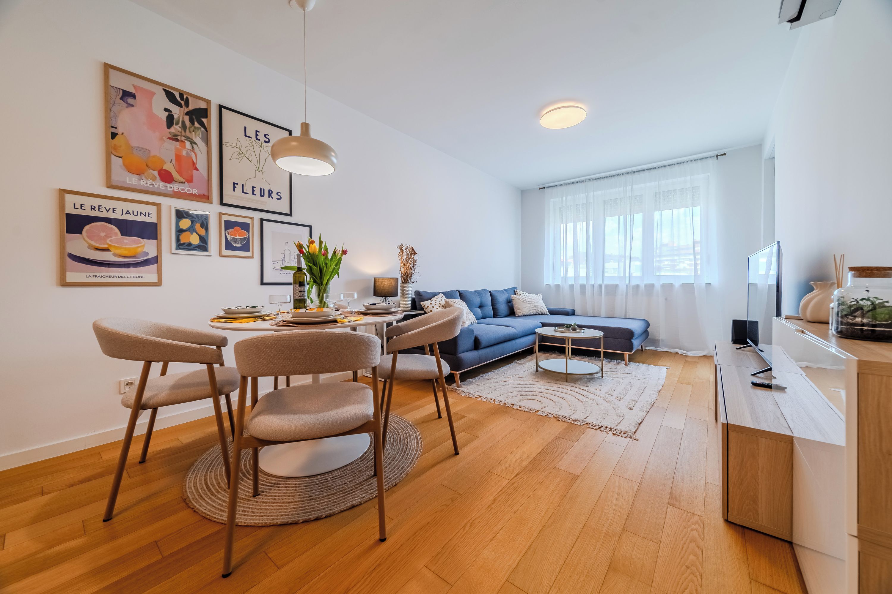 Ein modernes Wohnzimmer mit Essbereich, einer Couch und einem Fernseher.