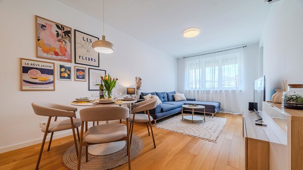 Een moderne woonkamer met een eethoek, een bank en een televisie.