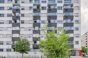 A multi-story residential building with balconies, a visible storefront, and a clear sky. - Meandar Zagreb Apt w/ Garage & Terrace (Zagreb)