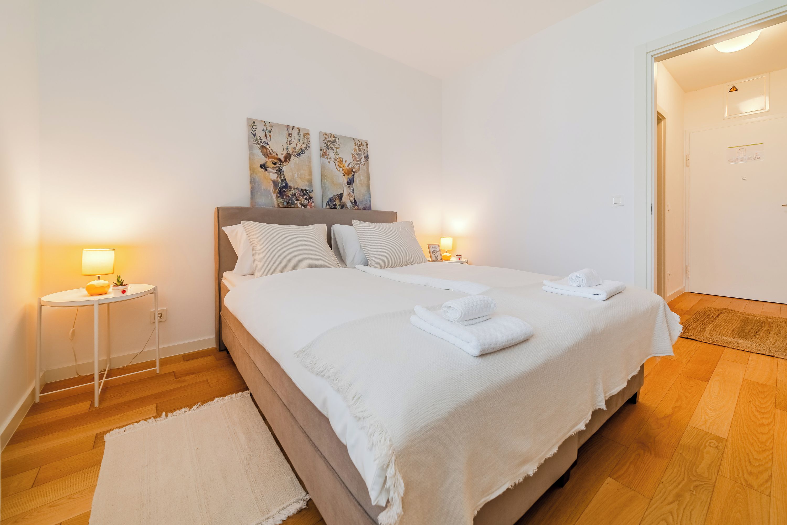 Une chambre à coucher bien rangée, avec un lit, des lampes de chevet et des œuvres d’art accrochées au mur.