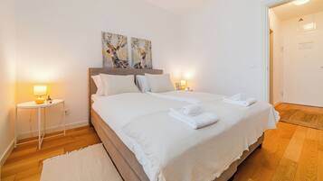 Une chambre à coucher bien rangée, avec un lit, des lampes de chevet et des œuvres d’art accrochées au mur.