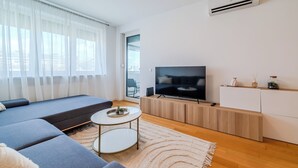 Una sala de estar moderna con un sofá, televisión y una pequeña mesa redonda.