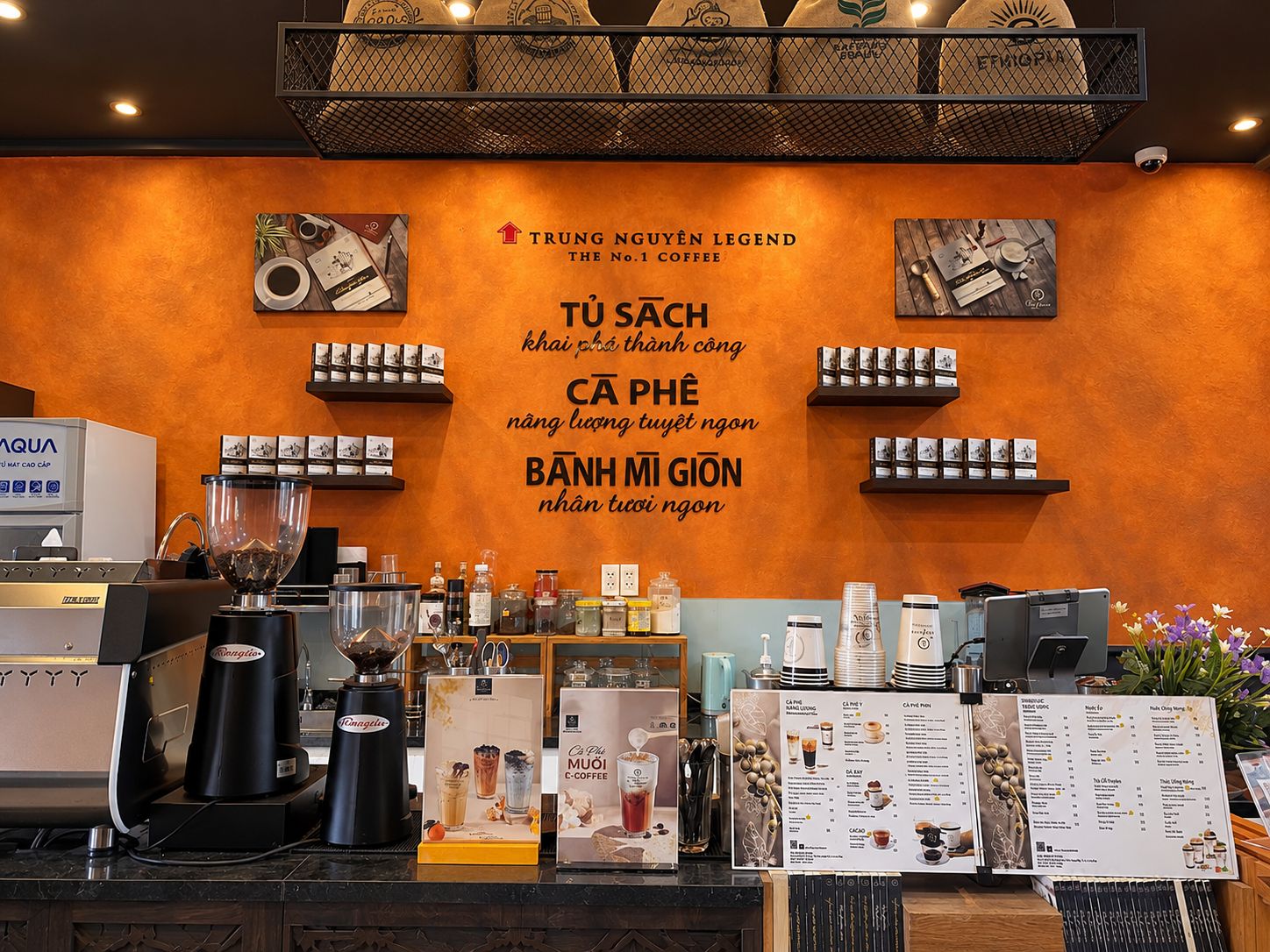 A coffee shop interior with a menu board, coffee machines, and various coffee-related items on display.