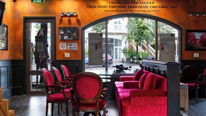 A restaurant interior with red upholstered chairs and sofas, a marble floor, and a view through a large window. - Jenben Hotel (Phu Quoc)