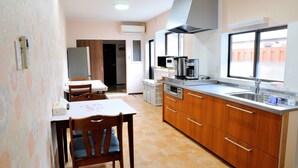 A kitchen with wooden cabinets, a microwave, a coffee maker, and a window with a view. - KAKENKAN (Miyazu)