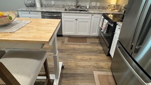 Une cuisine moderne avec des armoires blanches, un réfrigérateur en acier inoxydable et une table à manger en bois.