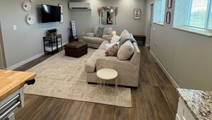 Un salon avec un canapé beige, un téléviseur et un plancher en bois.