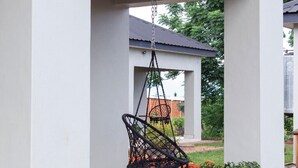 A hanging chair in a covered outdoor area with a potted plant nearby. - Chalo villa's and farm (Chitedze)