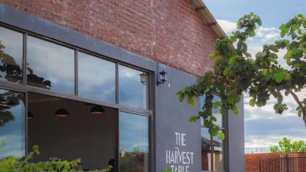 A building with a brick facade, large windows, and a sign reading 'THE HARVEST TABLE'. - Chalo villa's and farm (Chitedze)