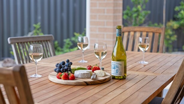 Et træbord med vin, glas, druer, jordbær og ost.