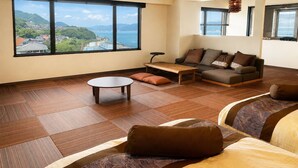 A modern living room with a large window, a sofa, a coffee table, and a patterned rug.
