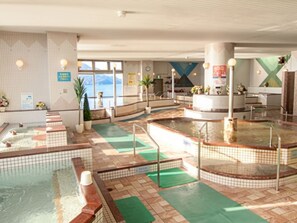 A spa area with multiple hot tubs, a reception desk, and a view of the sea. - Livemax Resort Mihara Sea Front (Mihara)