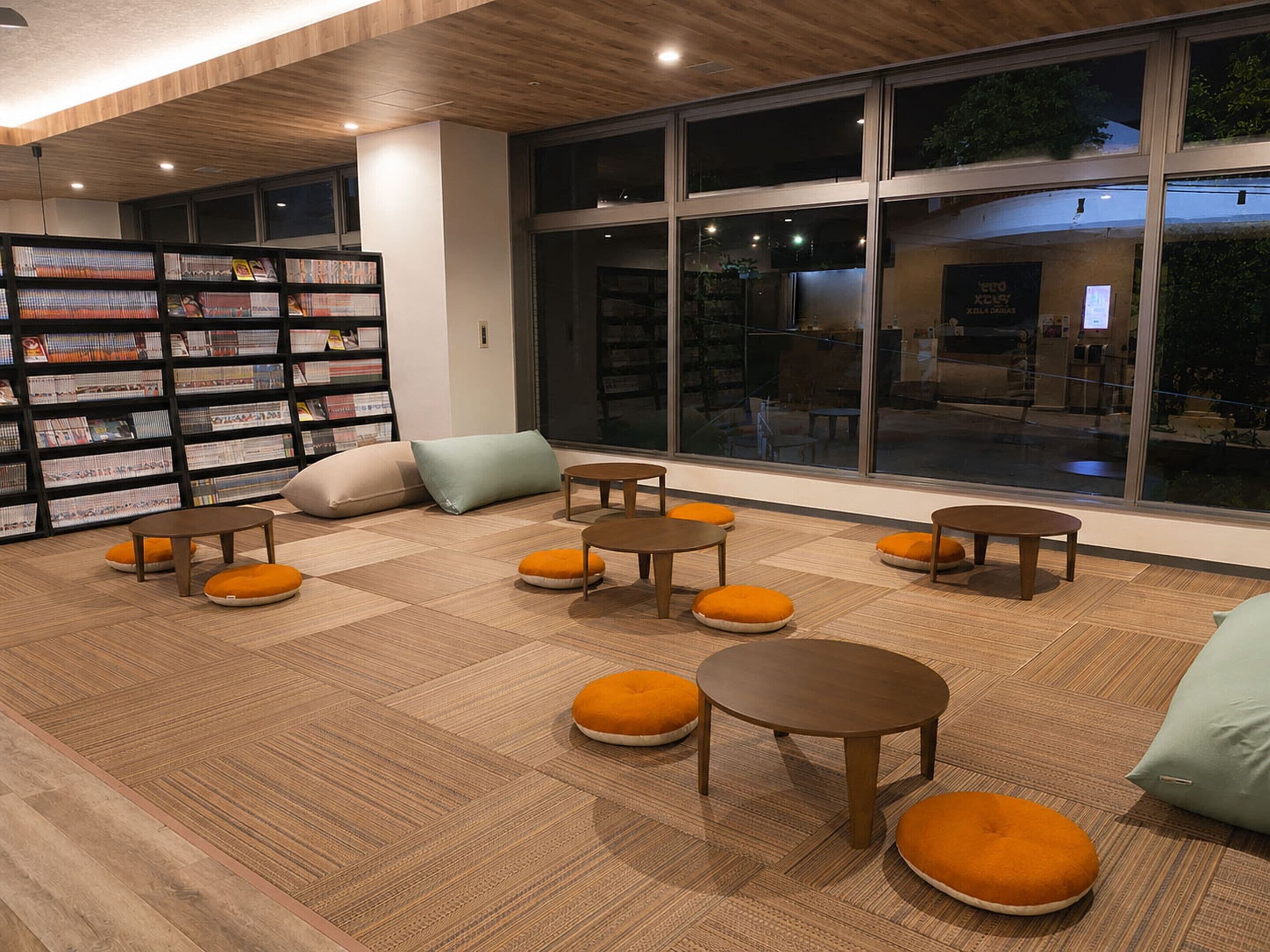 Interior moderno de biblioteca con estanterías, zonas de descanso y grandes ventanales.