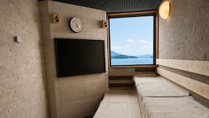 A room with a large window, a flat-screen TV mounted on the wall, and a bench with a textured fabric cover.